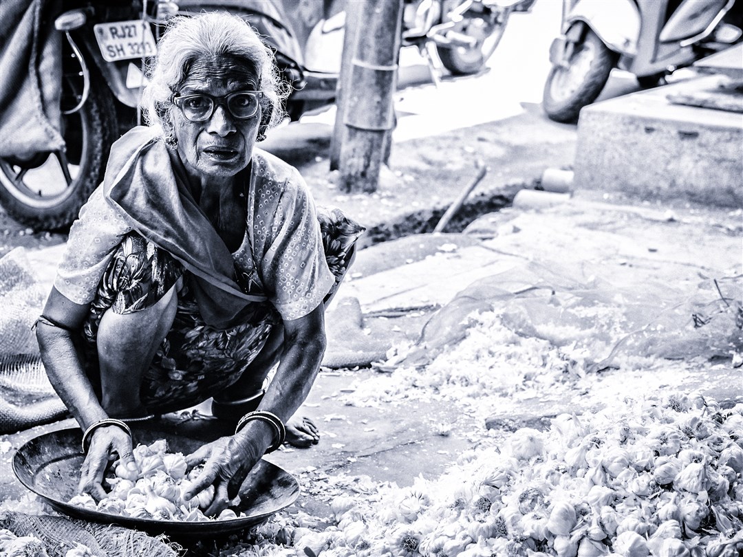 An old woman sorts out garlics at a local market.