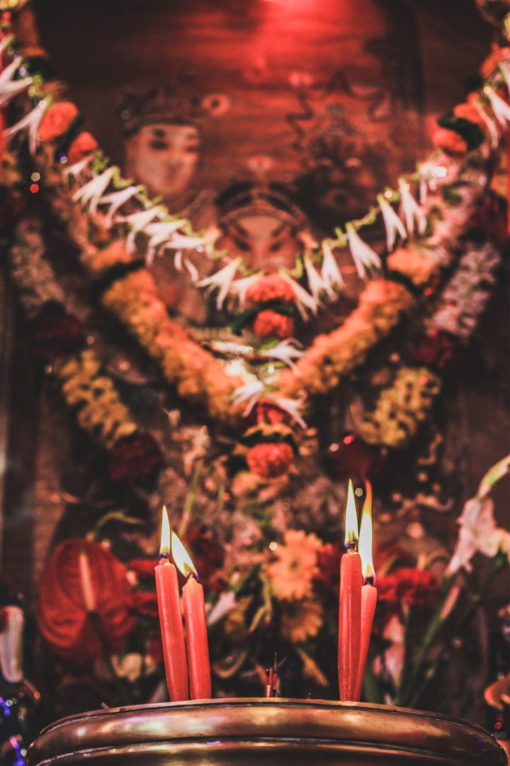 Candles lit up in front of a picture of the deity.